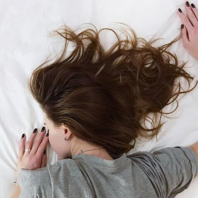 A girl sleeping face-front on a bed