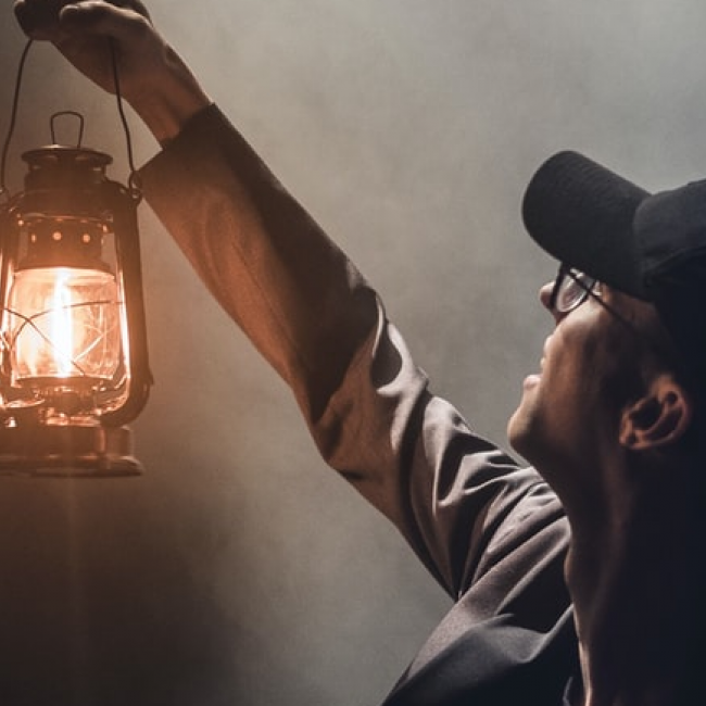 Man holding lantern in darkness