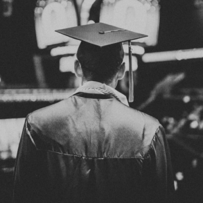 a black and white photo of the back of a graduate wearing a cap and gown
