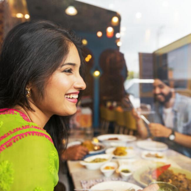 girl smiling looking to the side while food is behind her on the table 