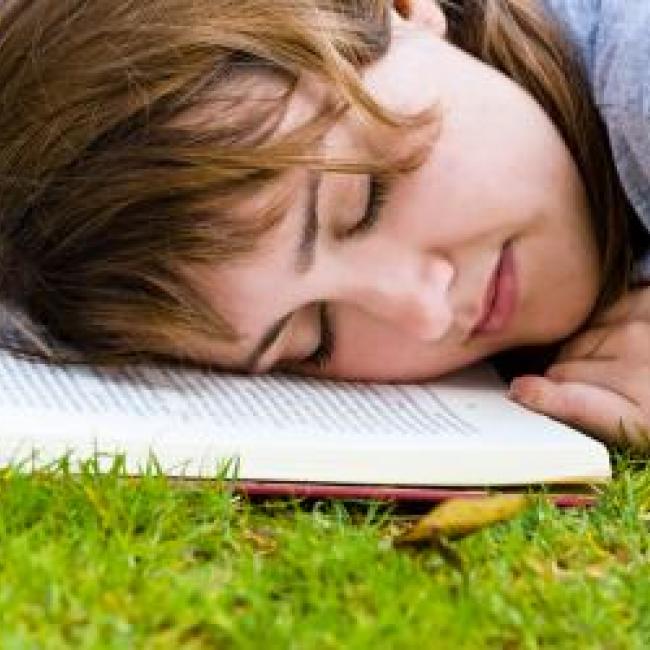 Girl sleeping on a book on the grass