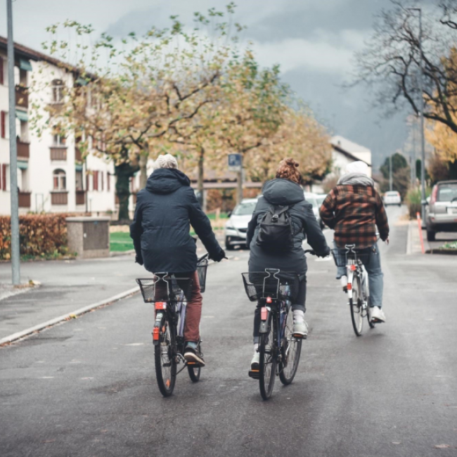 Three people riding their bikes down a road.
