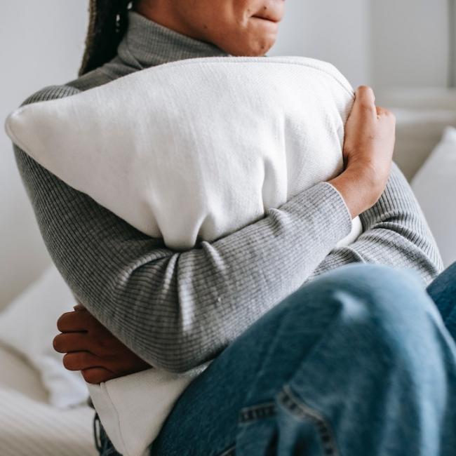 A person anxiously hugging a pillow