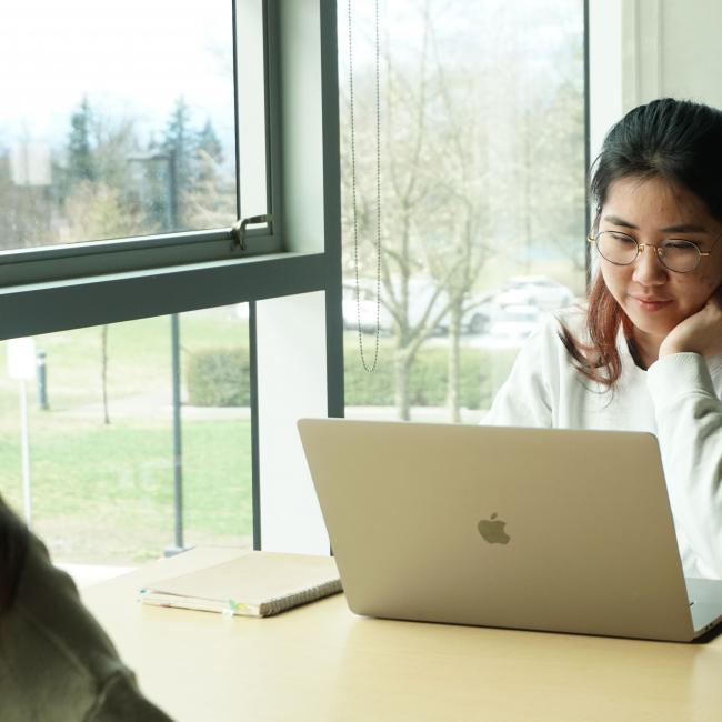 Student sitting at a table working on a laptop